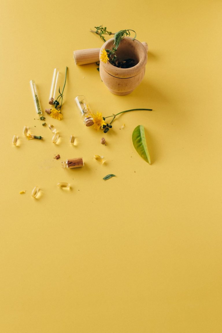 Natural herbal supplements and remedies displayed with a mortar and pestle on a vibrant yellow surface.